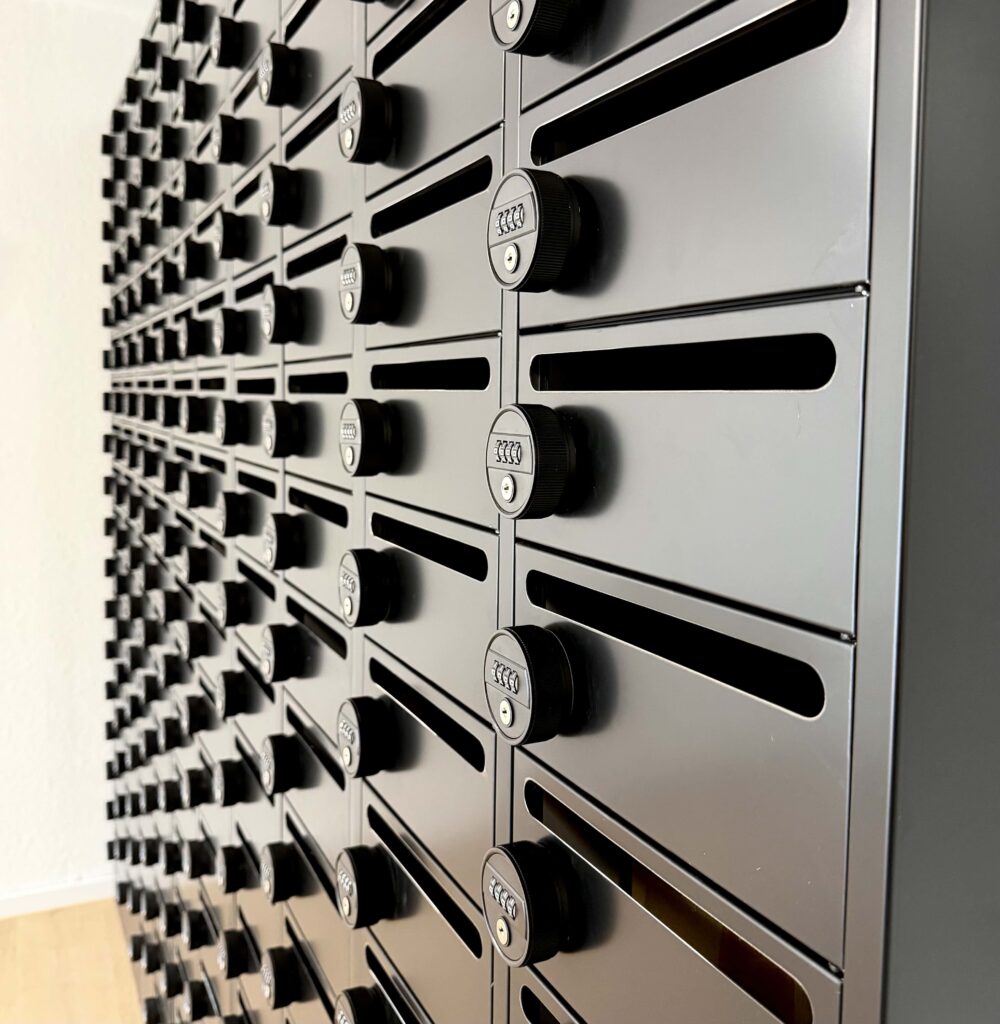 Schwarze Briefkastenanlage mit Zahlenschlössern bei Smarvo, modernes Design an einer hellen Wand.