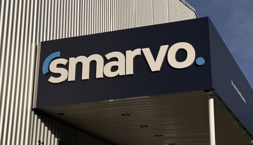 Smarvo Firmenlogo an einer modernen Gebäudefassade mit dunkelblauer Verkleidung und weißer Schrift, fotografiert bei Tageslicht.