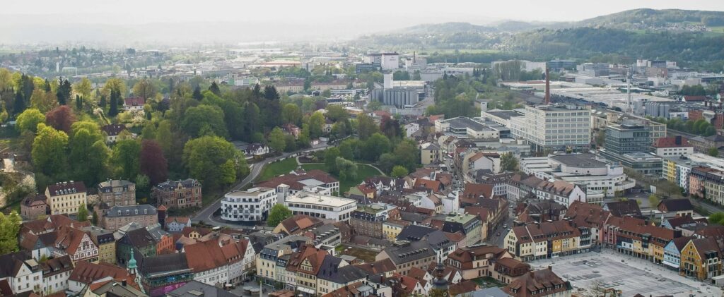 Luftaufnahme einer deutschen Stadt mit historischen und modernen Gebäuden sowie Grünflächen. Symbolbild für den entscheidenden Standortfaktor bei der Gewerbesteuer.