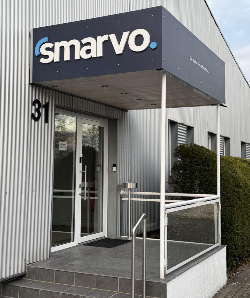 Der repräsentative Eingangsbereich des Smarvo Firmengebäudes mit Logo-Schild und der Hausnummer 31.