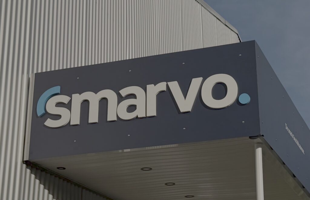 Smarvo Firmenlogo an einer modernen Gebäudefassade mit dunkelblauer Verkleidung und weißer Schrift, fotografiert bei Tageslicht.
